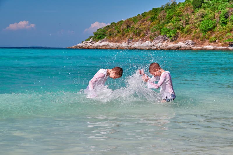 De kinderen hebben pret het spelen in het overzees op blauwe achtergrond De jongens bespatten water op elkaar Concept familievaka royalty-vrije stock afbeeldingen De kinderen hebben pret het spelen in het overzees op blauwe achtergrond De jongens bespatten water op elkaar Concept familievaka royalty-vrije stock afbeeldingen