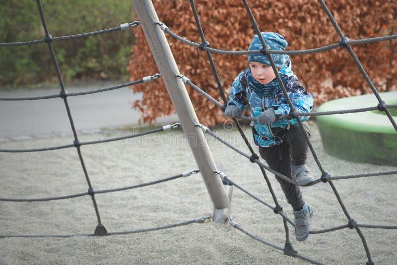 De kleine jongen beklimt de touwladder bij speelplaats in de lente stock afbeeldingen De kleine jongen beklimt de touwladder bij speelplaats in de lente stock afbeeldingen