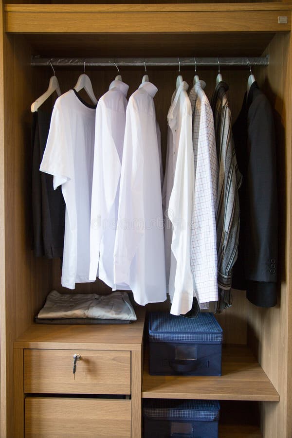 De kleren hangen op een plank in een ontwerper kleden opslag, moderne kast met rij van doeken die in garderobe, uitstekende ruimt stock afbeeldingen De kleren hangen op een plank in een ontwerper kleden opslag, moderne kast met rij van doeken die in garderobe, uitstekende ruimt stock afbeeldingen