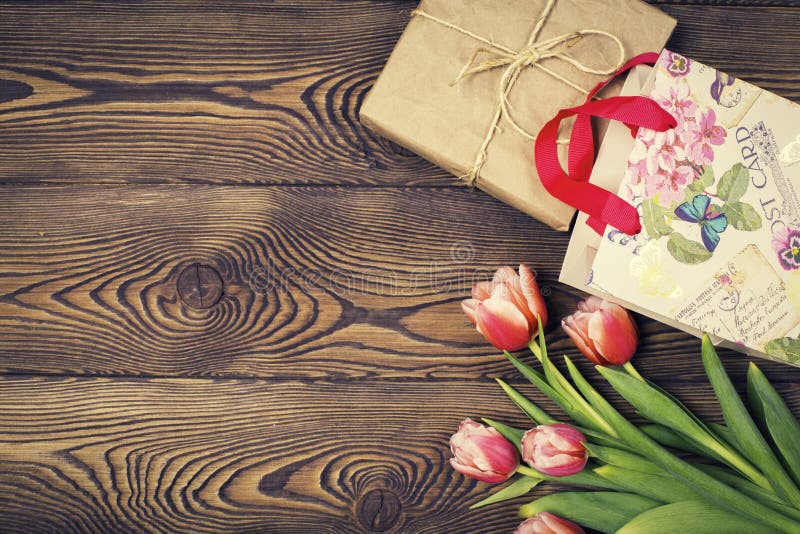 De kleurrijke tulpen en de gift in ambachtdocument en de gift doen op een houten lijst in zakken Hoogste mening met exemplaarruim royalty-vrije stock foto's De kleurrijke tulpen en de gift in ambachtdocument en de gift doen op een houten lijst in zakken Hoogste mening met exemplaarruim royalty-vrije stock foto's