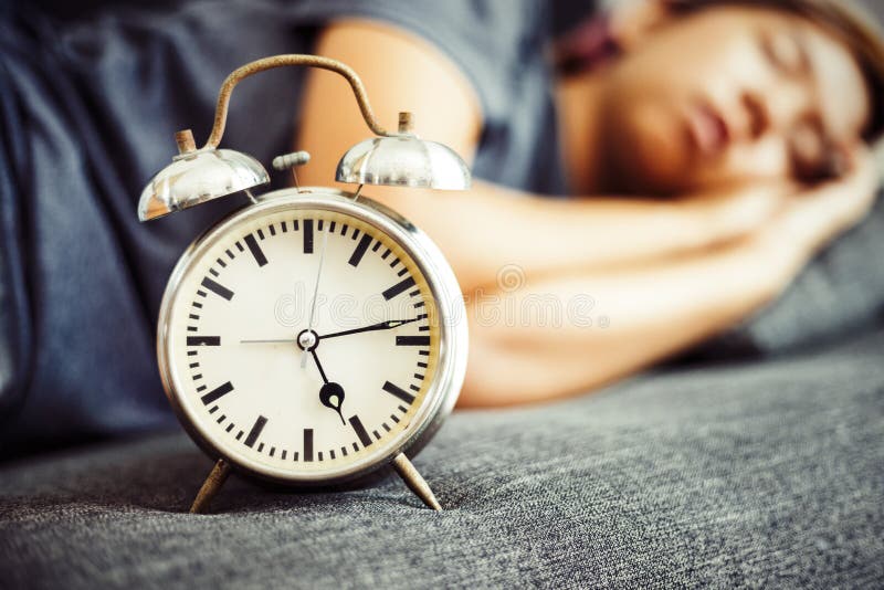 De klok is op het bed dichtbij vrouwen het slapen royalty-vrije stock fotografie De klok is op het bed dichtbij vrouwen het slapen royalty-vrije stock fotografie