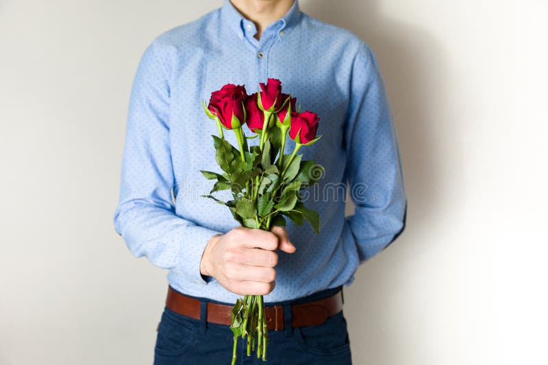 De knappe jonge mens die rood nam boeket, de romantische verrassing van de Valentijnskaartendag, liefde, bloemen houden toe stock foto De knappe jonge mens die rood nam boeket, de romantische verrassing van de Valentijnskaartendag, liefde, bloemen houden toe stock foto