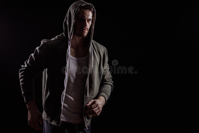 De knappe jonge mens met snor en de baard geen binnen sweatshort met kap royalty-vrije stock foto De knappe jonge mens met snor en de baard geen binnen sweatshort met kap royalty-vrije stock foto
