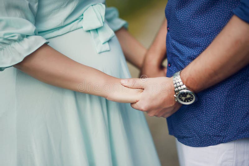 De knappe Kaukasische handen van de paarholding met nadruk op de mooie ronde baby van de zwangere vrouw stoten stock afbeeldingen De knappe Kaukasische handen van de paarholding met nadruk op de mooie ronde baby van de zwangere vrouw stoten stock afbeeldingen