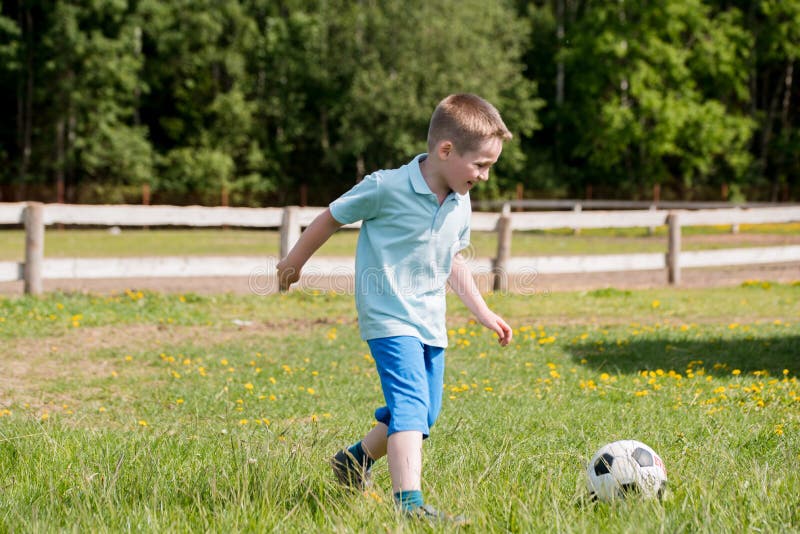 De knappe papa met zijn kleine leuke zon heeft pret en speelt Amerikaanse voetbal op groen grasrijk gazon stock foto De knappe papa met zijn kleine leuke zon heeft pret en speelt Amerikaanse voetbal op groen grasrijk gazon stock foto