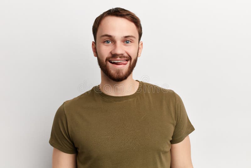De knappe speelse jonge mens draagt groene t-shirt, toont tong stock fotografie De knappe speelse jonge mens draagt groene t-shirt, toont tong stock fotografie