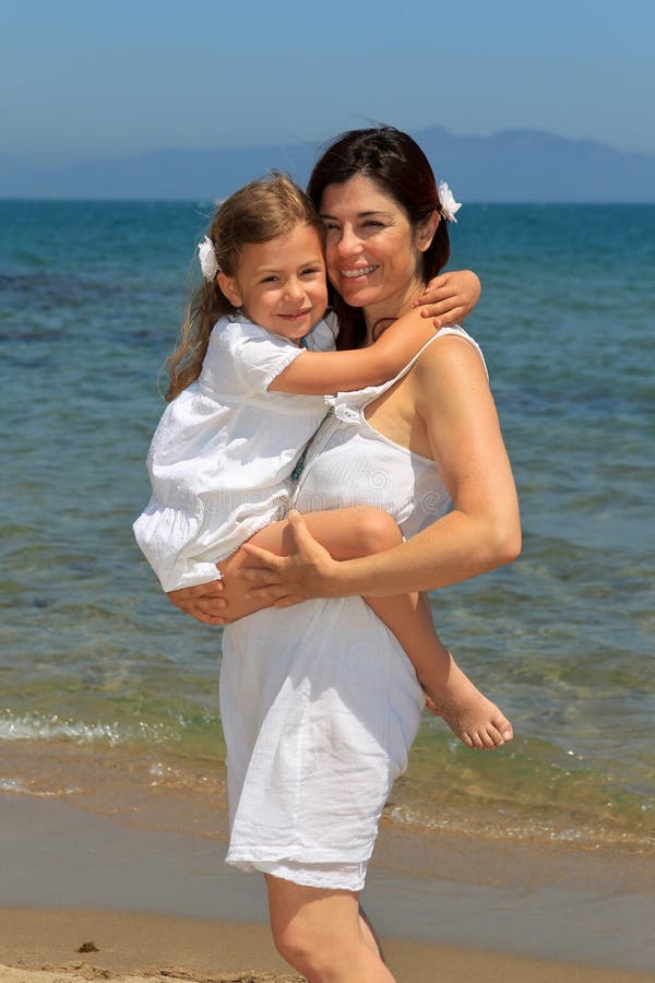 De knuffelende dochter van de moeder op een strand