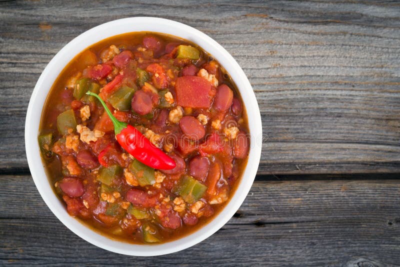 Pork chili con carne bowl over a wood textured background. Pork chili con carne bowl over a wood textured background