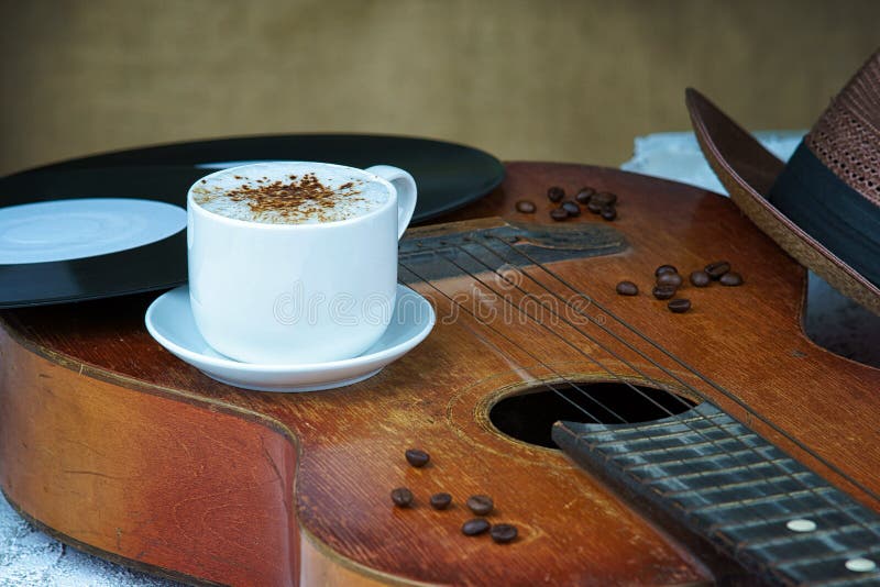 De kop van de cappuccinokoffie, gitaar, hoed en vinylplaat stock foto's De kop van de cappuccinokoffie, gitaar, hoed en vinylplaat stock foto's