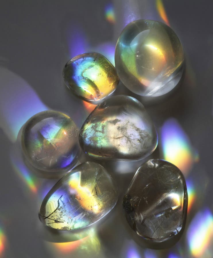 Close up of Quartz Crystal tumbled stones catching an array of rainbow spectrum colours on a grey background. Close up of Quartz Crystal tumbled stones catching an array of rainbow spectrum colours on a grey background
