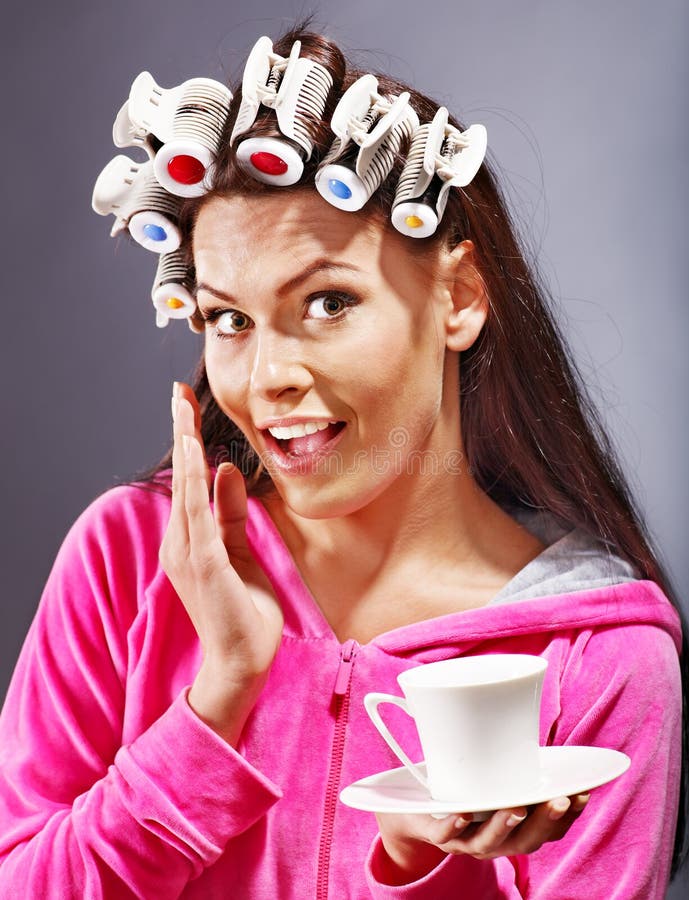 Woman wear hair curlers on head holding cup of coffee. Woman wear hair curlers on head holding cup of coffee.