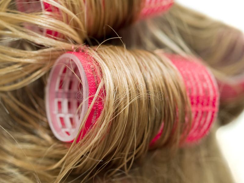 A close-up of red curlers in blond hair. A close-up of red curlers in blond hair