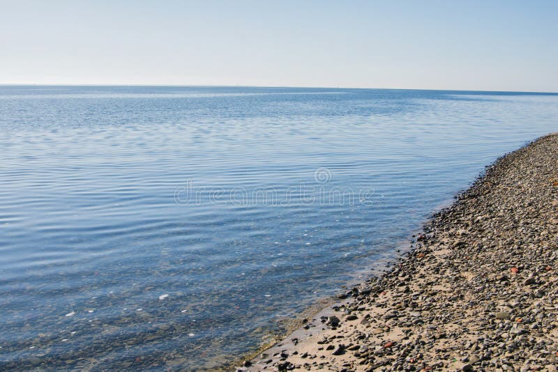 De kust van de grote rivier Stenen op het strand en in het water stock afbeelding De kust van de grote rivier Stenen op het strand en in het water stock afbeelding
