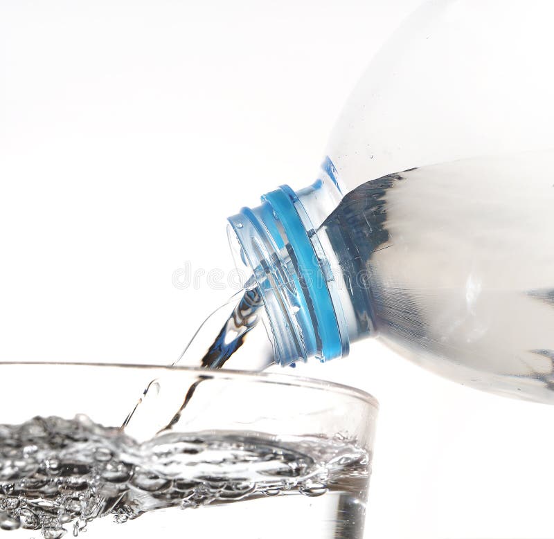 De l'eau potable est versée d'une bouteille dans un verre sur le CCB blanc photographie stock De l'eau potable est versée d'une bouteille dans un verre sur le CCB blanc photographie stock