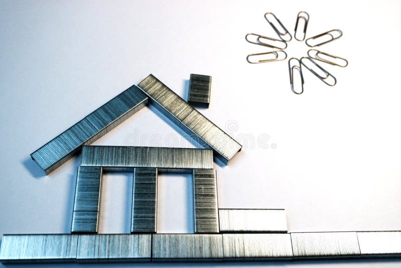 De las grapas de la grapadora se hace una casa en el Libro Blanco, sobre la casa de los clips de papel, el sol, pintura de la ofi fotografía de archivo De las grapas de la grapadora se hace una casa en el Libro Blanco, sobre la casa de los clips de papel, el sol, pintura de la ofi fotografía de archivo