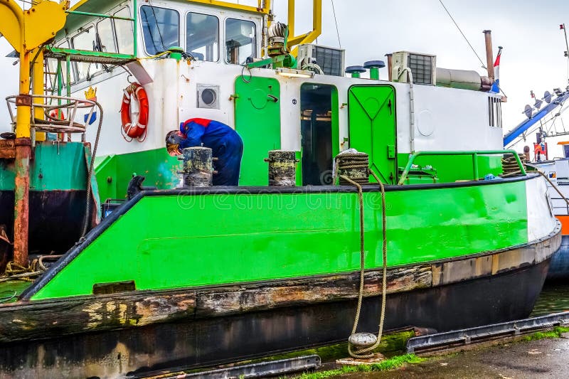 De lasser die Meerpalen op een Groot de Baggermachineschip van de Snijderszuiging herstellen verankerde voor reparaties in Urk in stock foto's De lasser die Meerpalen op een Groot de Baggermachineschip van de Snijderszuiging herstellen verankerde voor reparaties in Urk in stock foto's