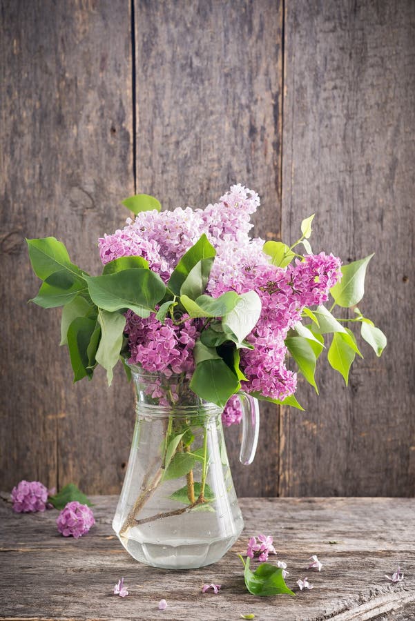 De lenteboeket van lilac bloemen in glasvaas op houten lijst royalty-vrije stock foto De lenteboeket van lilac bloemen in glasvaas op houten lijst royalty-vrije stock foto