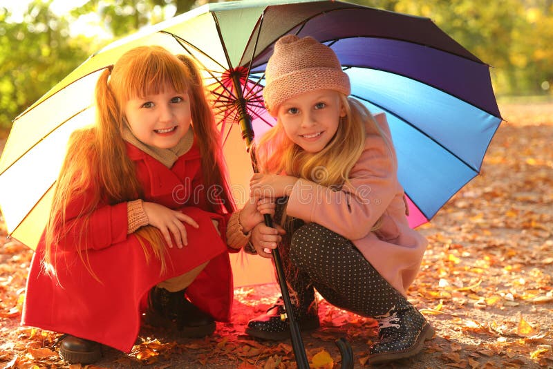De leuke meisjes met kleurrijke paraplu in de herfst parkeren royalty-vrije stock fotografie De leuke meisjes met kleurrijke paraplu in de herfst parkeren royalty-vrije stock fotografie