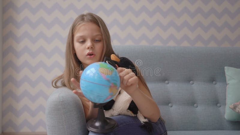 De leuke meisjesholding en roteert een kleine bol terwijl thuis het zitten op bank