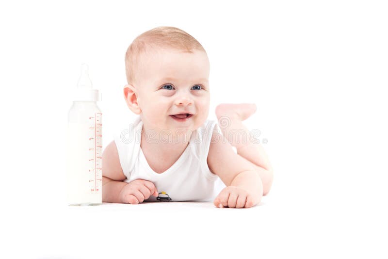 De leuke mooie babyjongen in wit overhemd ligt op buik met melk bott royalty-vrije stock foto De leuke mooie babyjongen in wit overhemd ligt op buik met melk bott royalty-vrije stock foto