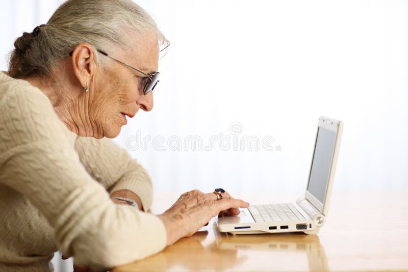 Elderly woman typing on ultra portable laptop computer. Shallow DOF. Elderly woman typing on ultra portable laptop computer. Shallow DOF.
