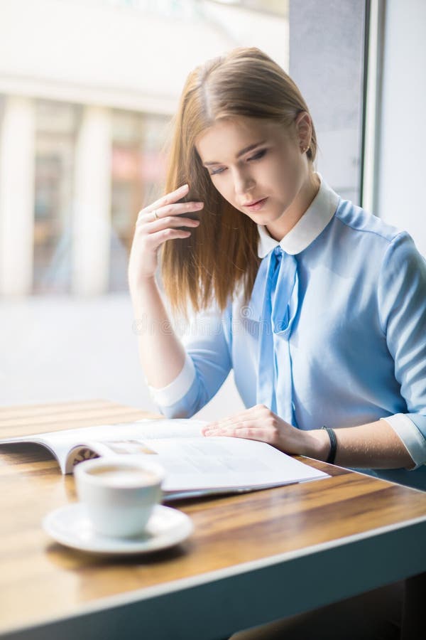 Vrouw die een tijdschrift leest in een café royalty-vrije stock foto's