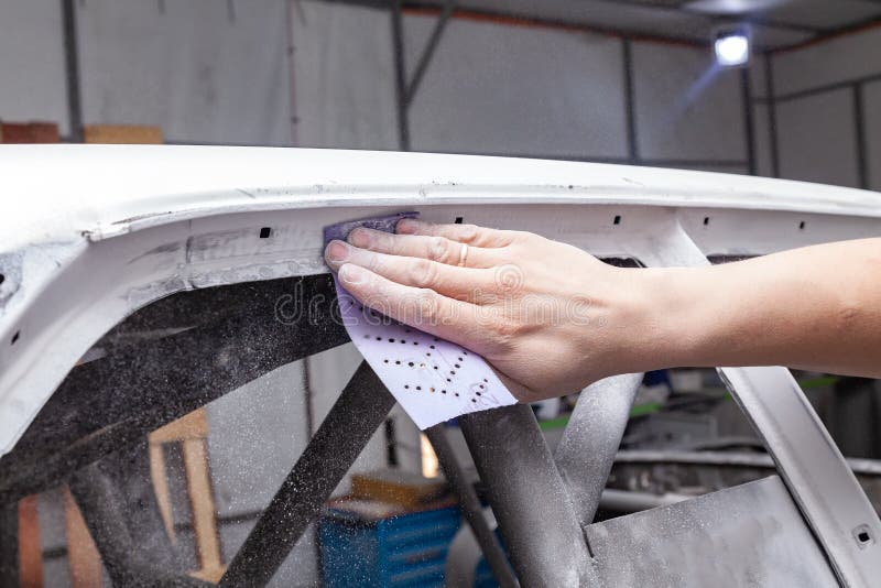 De lichaamshersteller maalt het kader van de witte auto met purper amarildocument als voorbereiding op het schilderen na het toep