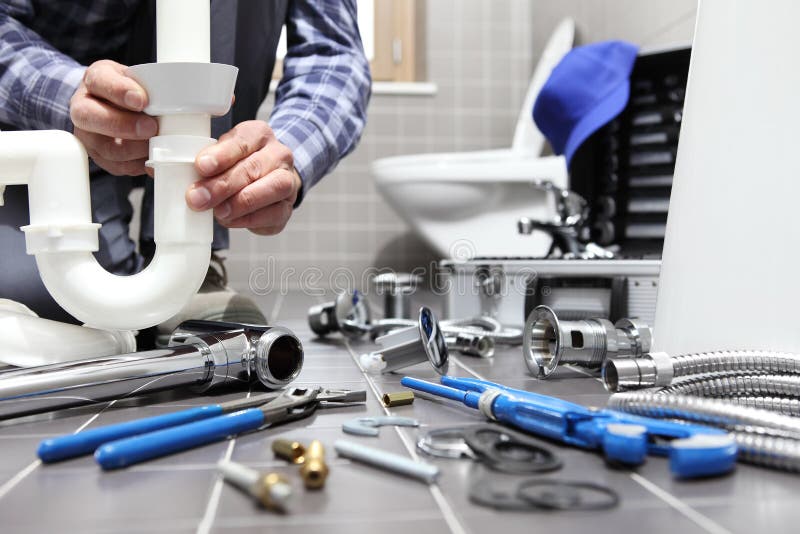 De loodgieter aan het werk in een badkamers, de dienst van de loodgieterswerkreparatie, assembleert De loodgieter aan het werk in een badkamers, de dienst van de loodgieterswerkreparatie, assembleert