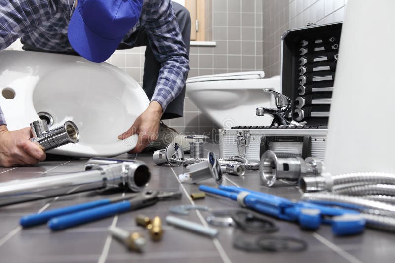De loodgieter aan het werk in een badkamers, de dienst van de loodgieterswerkreparatie, assembleert stock foto De loodgieter aan het werk in een badkamers, de dienst van de loodgieterswerkreparatie, assembleert stock foto