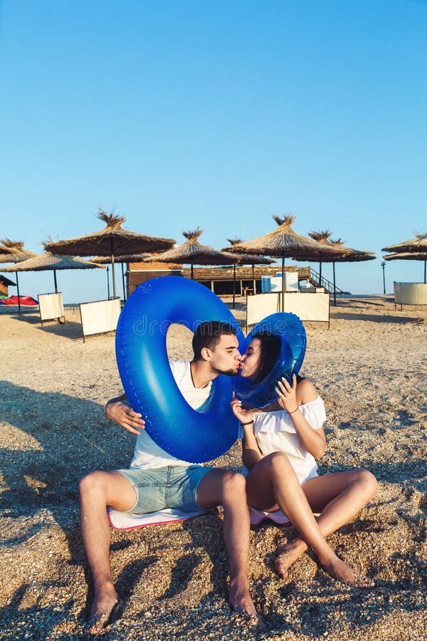 De man en de vrouw zitten op het strand en houden opblaasbare cirkels concept de zomer overzeese vakantie royalty-vrije stock foto De man en de vrouw zitten op het strand en houden opblaasbare cirkels concept de zomer overzeese vakantie royalty-vrije stock foto