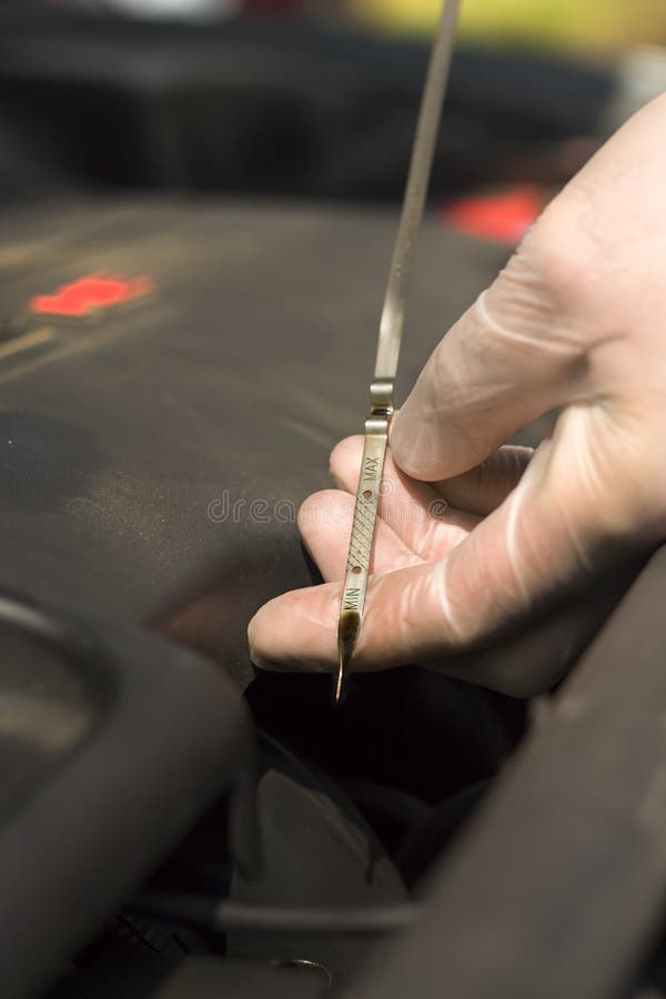 De man ` s dient beschikbare handschoenen in controleert het olieniveau in de motor stock foto De man ` s dient beschikbare handschoenen in controleert het olieniveau in de motor stock foto