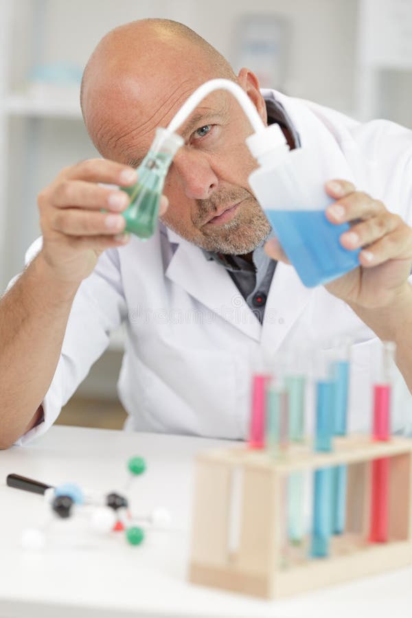 De mannelijke fles van de onderzoekersholding met blauwe vloeistof in laboratorium royalty-vrije stock fotografie De mannelijke fles van de onderzoekersholding met blauwe vloeistof in laboratorium royalty-vrije stock fotografie
