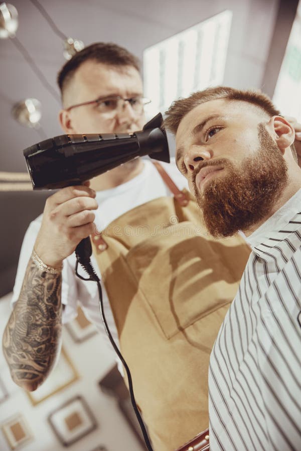 De mannelijke kapper droogt haar van zijn cliënt stock fotografie De mannelijke kapper droogt haar van zijn cliënt stock fotografie