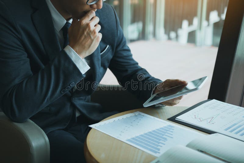 Male manager businessmen are looking at the tablet screen with the company`s financial information and he is tense about the performance. Male manager businessmen are looking at the tablet screen with the company`s financial information and he is tense about the performance.