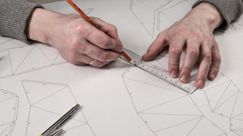 De mannelijke ontwerper maakt een werkende tekening Werkplaats van een stuk speelgoed ontwerper De tellers, de heerser, de pen en stock foto De mannelijke ontwerper maakt een werkende tekening Werkplaats van een stuk speelgoed ontwerper De tellers, de heerser, de pen en stock foto