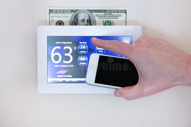 Male hand holding smart phone to operate heating or cooling of thermostat for home energy savings. Male hand holding smart phone to operate heating or cooling of thermostat for home energy savings