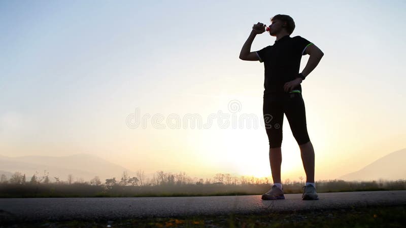 De marathonagent drinkt water op het brede landschap van de hoekberg