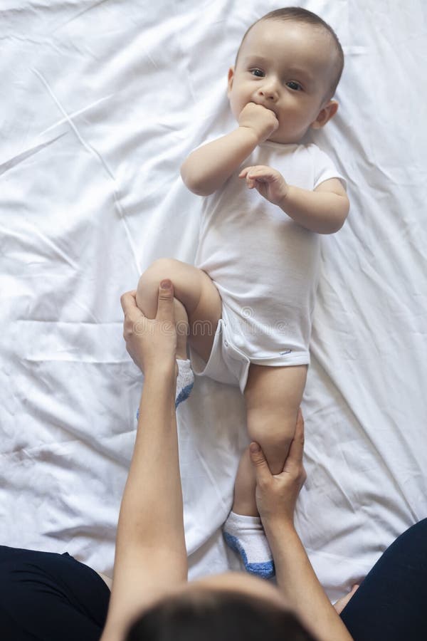 De massage van de baby Mamma dat gymnastiek met jong geitje doet Mama die leuke babyjongen masseren De bewegende benen van de bab stock afbeelding De massage van de baby Mamma dat gymnastiek met jong geitje doet Mama die leuke babyjongen masseren De bewegende benen van de bab stock afbeelding