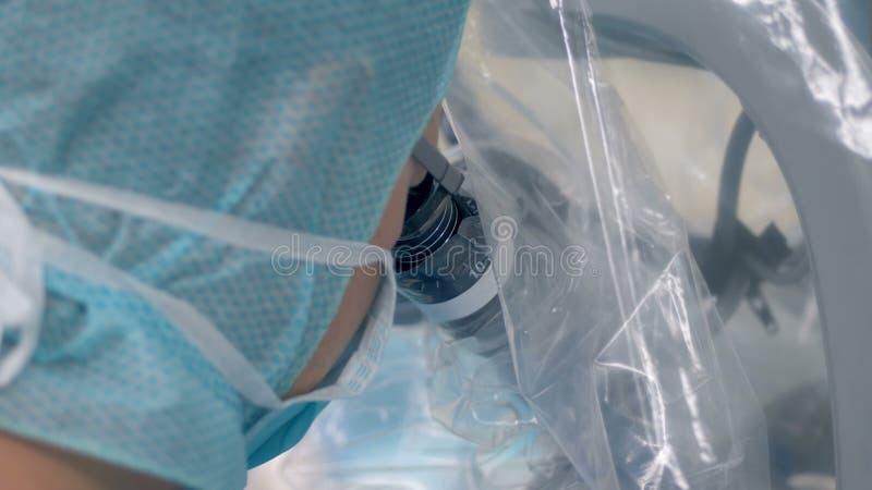 De medische arbeider kijkt in een microscoop tijdens chirurgie 4K