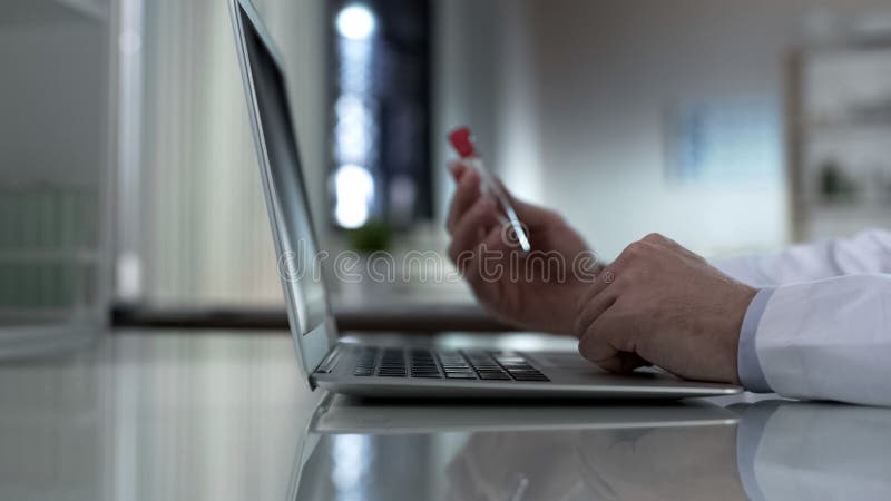 De medische reageerbuis van de onderzoekersholding, het typen informatie over laptop, rapport stock afbeeldingen De medische reageerbuis van de onderzoekersholding, het typen informatie over laptop, rapport stock afbeeldingen