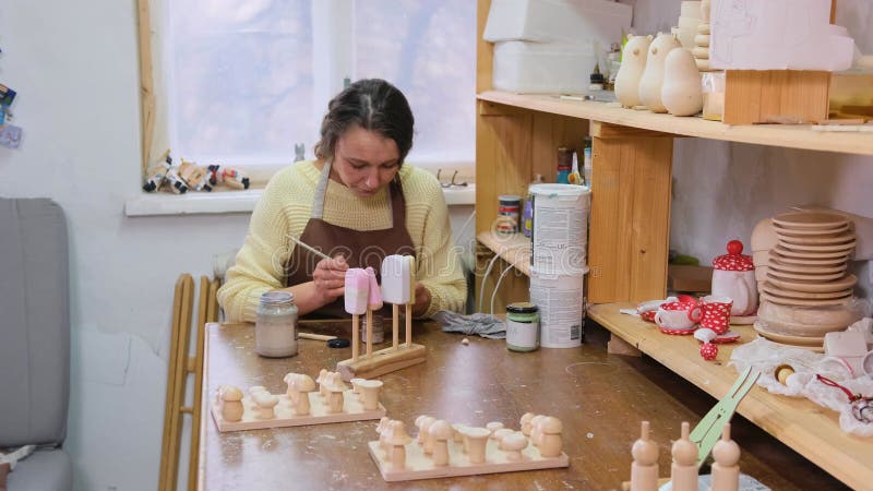 De meester schildert houten speelgoed met acrylverven. productie van milieuvriendelijk speelgoed voor kinderen