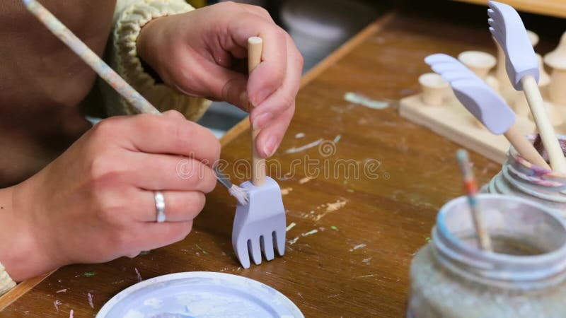 De meester schildert houten speelgoed met acrylverven. productie van milieuvriendelijk speelgoed voor kinderen