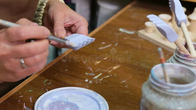 De meester schildert houten speelgoed met acrylverven. productie van milieuvriendelijk speelgoed voor kinderen