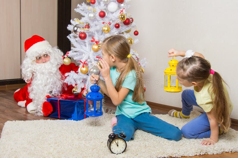 De meisjes met flitslichten om Santa Claus te zien die probeerde om discreet te zetten stelt onder de Kerstboom voor royalty-vrije stock foto's De meisjes met flitslichten om Santa Claus te zien die probeerde om discreet te zetten stelt onder de Kerstboom voor royalty-vrije stock foto's