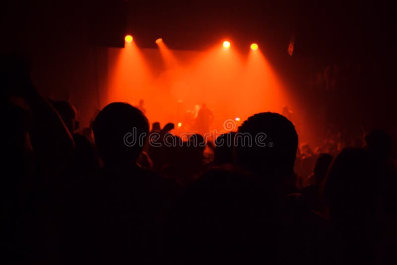 De menigte van publiekssilhouetten in grote concertzaal het letten op rots toont stock foto De menigte van publiekssilhouetten in grote concertzaal het letten op rots toont stock foto