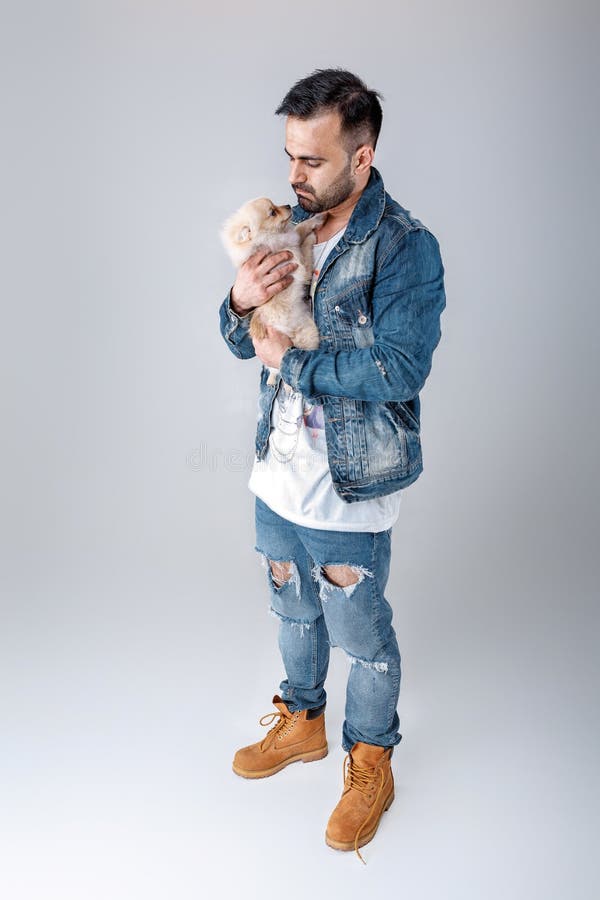 De mens in denimjasje houdt pomeranian hond stock afbeelding De mens in denimjasje houdt pomeranian hond stock afbeelding