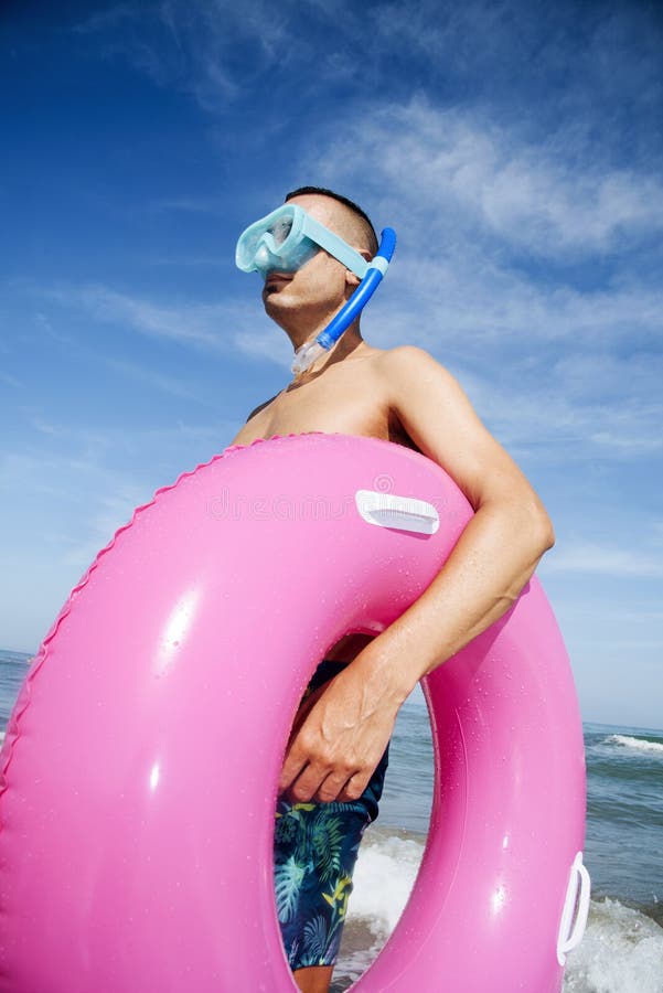 De mens op het strand met het duiken masker en zwemt ring royalty-vrije stock fotografie De mens op het strand met het duiken masker en zwemt ring royalty-vrije stock fotografie