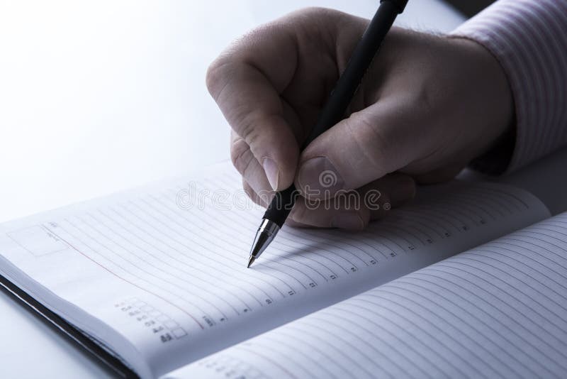 Diary and human hand holding a pen close-up. Diary and human hand holding a pen close-up