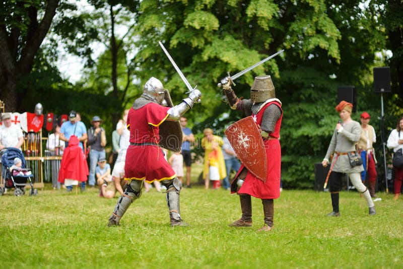 De mensen die ridderkostuums dragen vechten tijdens het historische weer invoeren op jaarlijks Middeleeuws die Festival, in het P stock afbeelding De mensen die ridderkostuums dragen vechten tijdens het historische weer invoeren op jaarlijks Middeleeuws die Festival, in het P stock afbeelding