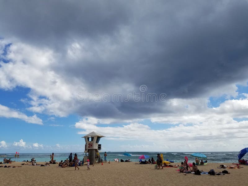 De mensen hangen uit bij strand met golvend water op oceaan van Kaimana zijn royalty-vrije stock afbeelding De mensen hangen uit bij strand met golvend water op oceaan van Kaimana zijn royalty-vrije stock afbeelding